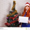 young-beautiful-redhead-woman-santa-cap-holding-empty-boar-women-board-hands-free-space-advertisement-text-mockup-115713339